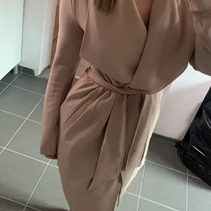 Beige kappa  - Beige kappa med band i midjan. Använd ett fåtal gånger. 