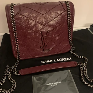 Saint Laurent väska - Jättefin och snygg väska i modell, Niki från Saint Laurent.  Väskan är i en lite mörkare röd och är oanvänd, det finns inga defekter på den. Denna modell finns inte längre att köpa och jag köpte den för 1 år sedan. Äkthetsintyg finns! Den är 15x18cm (höjdxbredd) o bandet är 56cm långt❤️💓