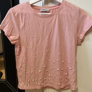 Cropped t-shirt with pearls - Croppad ljusrosa t-shirt med pärlor. Strl M men är enligt mig väldigt liten i storleken så skulle mer säga att den är XS/S 