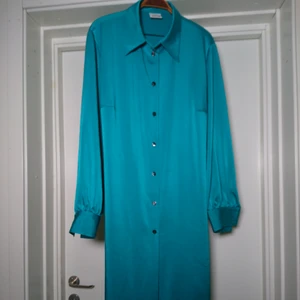 Vintageklänning/tunika - Så fin klänning/tunika i fantastisk turkos färg. Knyts i midjan eller has "utsläppt"? Ingen storleksmärkning men den bör vara en L/XL. Funkar även på M iom att den kan regleras med banden i midjan🌺