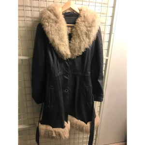 Blå skinnjacka med pälskrage  - Säljer min älskade mörkblå skinnkappa med fårpälsdetaljer, pga flytt.. Fodrad och varm. Troligtvis 70-tal. Utmärkt vintage skick. Buda gärna 