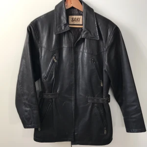 Skinnjacka med spännen  - Coolaste mörkbruna skinnjackan (äkta) från det kända skinnmärket Saki. Så snygg passform verkligen med spännen i midjan man kan spänna så mycket som man vill. Passar XS-L beroende på hur man vill att den sitter 