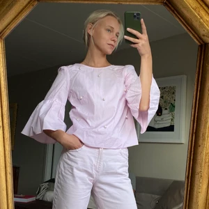 Gullig blus med pärlor och volangärm - Supersöt blus med pärlor framtill och stora volangärmar. Knapp baktill borta, går enkelt att du dit en ny. Säljer en likadan blus i blått samt jeansen på bilden. Se separata annonser.