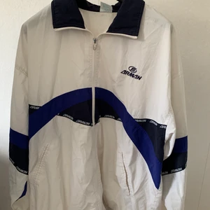 Jacka - En vit vintage jacka med svarta och blåa detaljer, med fickoroch en fin detalj i ryggen