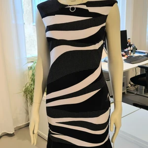 Klänning Frank Lyman  - Figurnära klänning i svart/vitt mönster. Dold dragkedja i ryggen. Volangkant nedtill och en lättburen modell från Canadensiska high fashion Brand Frank Lyman. Butikspris 2995:-