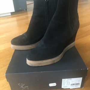 Skor från Filippa K - Stl 39. Fint begagnat skick. Några få märken på sulan. Sparsamt använda (ca 5 gånger) Svart mocka. Otroligt skön sko med kilklack, ca 8 cm. Köpta på Åhléns för 2399. Skopåse och orginalkartong.