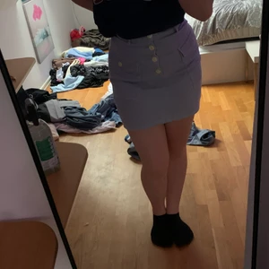Lila kort sommar kjol - En kort lila kjol med lite räfflad yta. Vita knappar och fickor på sidorna. Knappt använd och sitter fint. Den är dock väldigt kort så jag rekommenderar att dra ner den lite när man har på sig den. 26kr frakt