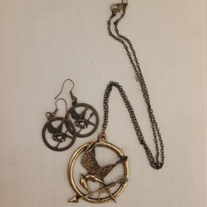 Hungerspelen-smycken - Mycket fint set av Mockingjay-smycken, halsband och örhängen. Har inte använts på flera år så tänkte att de skulle få ett nytt hem. Bra kvalitet men inte tunga i öronen. Felfritt skick 🔥