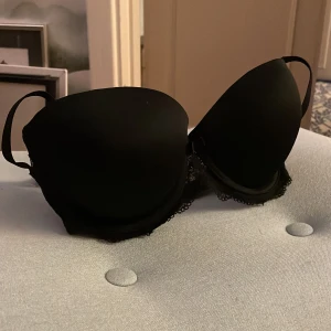 Svart BH Agio Milano 70F 70E - Svart balkonette-BH från Agio Milano. Pushup med avtagbar vaddering och axelband. Oanvänd med lapp kvar. Har även en av samma modell i storlek 70E