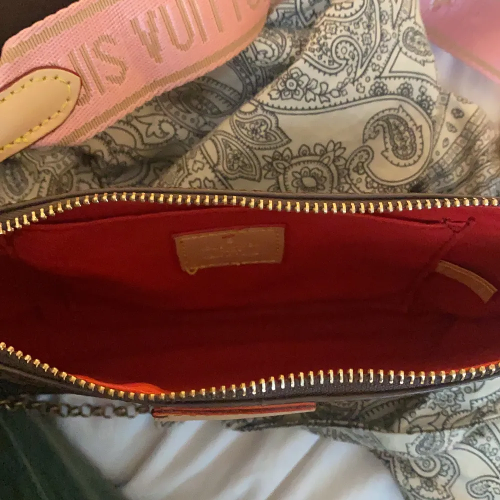En brun lv väska med rosa band med guld kedja. Säljer för 700 kr. Nästan aldrig använt den .. Väskor.