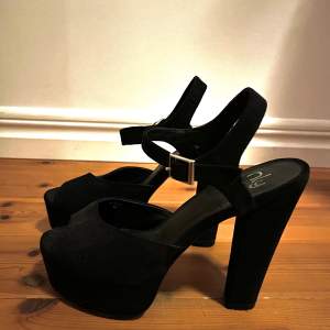 Svarta högklackade skor med platå i fakemocka från Nelly.com. Storlek 38. Använda en gång. I fint skick. Klackhöjd: 12 cm.  