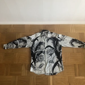 White blue - black Patterned  Shirt - Has small stains by the bottom edge of shirt, barely noticeable 