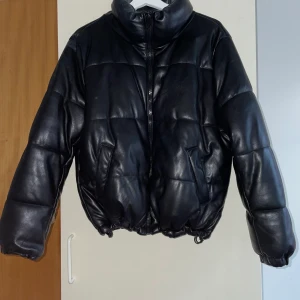 Amisu jacka - En svart och snygg fake skinn pufferjacka från märket Amisu. Storlek 40, den går att justera hur indragen jackan ska vara. 