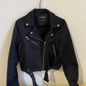 Höst/vårjacka i mockaimitation - Snygg höst/vårjacka i mockaimitation. Lite croppad i modellen och med extra långa ärmar. Endast använd ett par gånger - som i nyskick!