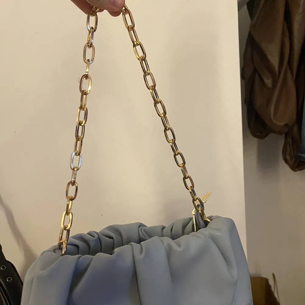 En blå skrynklig väska med äkta metall kedja i guld  Rymlig väska . Väskor.