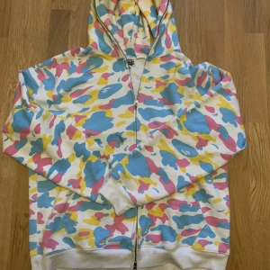 Bape hoodie - Säljer denna Bape zip up då den inte riktigt är min stil. Köpt second hand & är därför inte säker på att den är äkta men det ser så ut. Finns en liten fläck på bröstet (går säkert bort) men är i relativt bra skick annars. Skriv om ni vill ha fler bilder ☺️