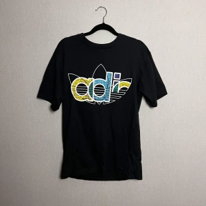 Adidas originals T-shirt med färglatt tryck - Snygg T-shirt med färgglatt tryck. Nypris är ca 800 kr, säljs i fint, använt skick. 