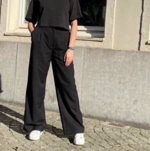 Monki svarta kostymbyxor  - Svarta kostymbyxor från monki(första bilden från deras hemsida) som tyvärr är för små i midjan. Har lagt ner byxbenen någon cm själv men det syns inte så mycket🖤🖤🖤Fraktar gärna men köparen står för kostnad.