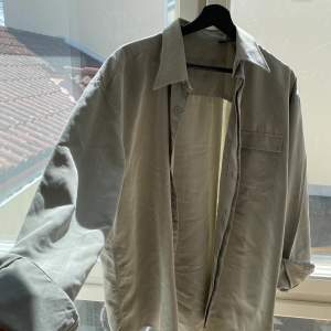Grå-beige skjorta i material, storlek L. Superfin kvalitet, nästan lite tungt material.