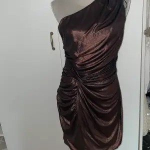 En brun/glittrig klänning som är väldigt fin! Aldrig fått chans att använda den därför säljs den!💓 fin knytning där fram!! Hur fin som helst den är från AX Paris