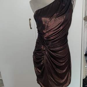 En brun/glittrig klänning som är väldigt fin! Aldrig fått chans att använda den därför säljs den!💓 fin knytning där fram!! Hur fin som helst den är från AX Paris