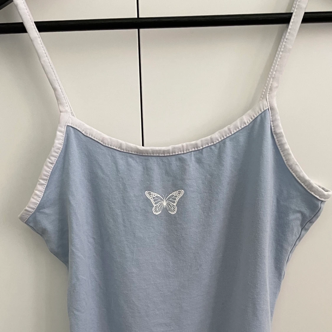 Ljusblå klänning får H&M med en vit tryckt fjäril på bröstet  - 90