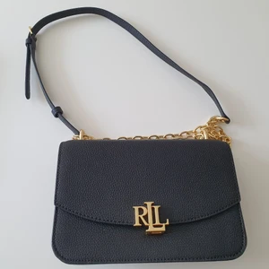 Ralph Lauren väska Madison  - RL väska Madison strl M. Svart med gulddetaljer. Stängs med spänne. Kedjerem 60 cm. Bredd 22 cm. Höjd 15 cm. Djup 8 cm. Present som inte kommer till användning. Använd ett fåtal tillfällen. Nypris 2595. Hämtas helst upp i hemmet eller centralt i Göteborg.