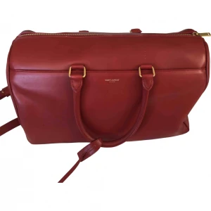 Saint laurent väska  - Duffle bag från saint laurent perfekt till skola/jobbar/resa Köpt på vestaire. Se bilder för skick (blixt så man ser alla repor) samt fläck inuti. Den har fack framtill och inuti + axelband. Skicka meddelande för mer info + bilder! Buda i chatten 