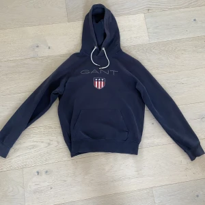 GANT Hoodie - Säljer nu en GANT hoodie då den inte passar mig längre. Fint skick förutom märke på armbågar (se bild 3). Storlek M Vid eventuella frågor eller funderingar är det bara att höra av sig!