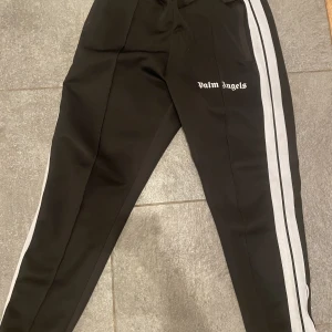 Palm angels byxor  - Säljer dessa svarta Palm Angels byxor då de inte kommer till användning. Byxorna är i storlek M. Köpte dem här på Plick för 1200kr. Kontakta mig gärna vid frågor/mer bilder osv. Kan även tänka mig byten