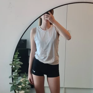 Nike träningslinne - Ett vitt träningslinne med nike loggan frampå, av lite längre modell. Använd några gånger.