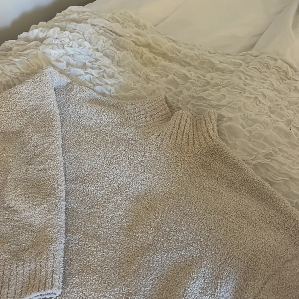 Halvhög krage i mjukaste materialet, mot teddy hållet. Neuleet.