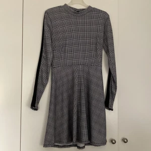 Klänning - En medellång vit klänning med svart rutat mönster & svarta tjocka ränder längs armarna från Gina Tricot. Aldrig använd, inga defekter. Storlek S & stretchigt  material. Matcha t.ex klänningen med ett par svarta boots🌟 80kr + frakt (köparen står för frakt)