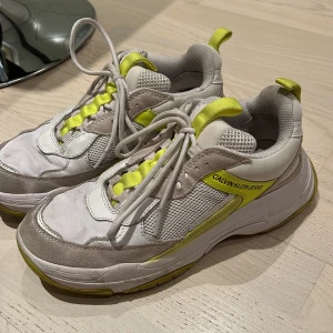 Calvin Klein sneakers - Sneakers (hög sula) från CK i beige/vitt och neongult. De är lite smutsiga men annars knappt använda. Går säkert att tvätta bort. Storlek 38.