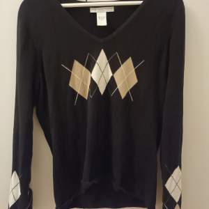 En svart v-ringad långärmad tröja med mönster på! Säljer då den aldrig kommit till användning.