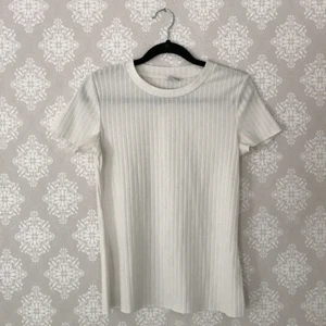 Vit ribbad t-shirt / topp - En vit ribbad t-shirt / topp som inte använts så mycket och därför är i gott skick. Storlek 158/164 men skulle vilja påstå att den även passar som en XS eller kanske till och med större beroende på hur man vill ha den🤍 Hör av er om ni har några frågor!