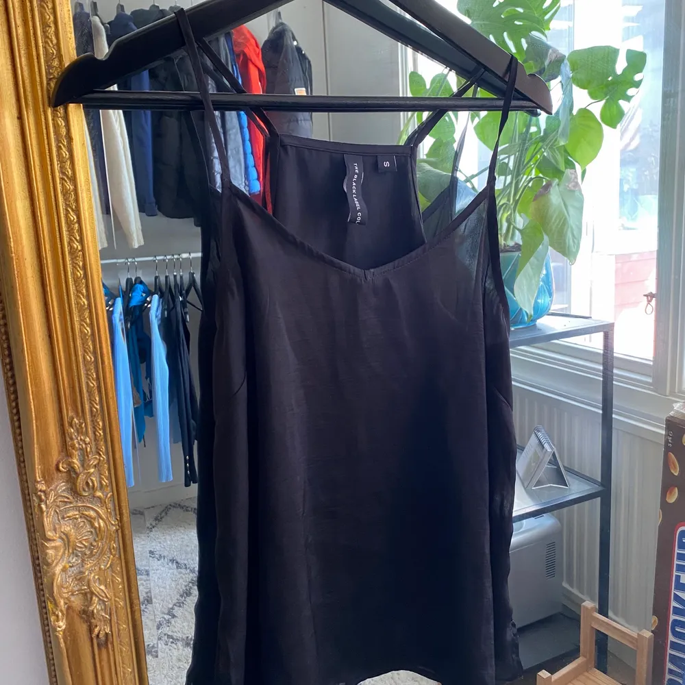 Ett svart linne i polyester från lager 157. Storlek 36/S. Toppar.