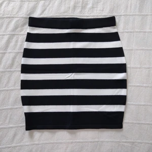 Svart/vit-randig kort kjol - Randig kort kjol. Mjuk och elastisk. Oanvänd från Bikbok. Storlek S. 75% viskos och 25% nylon. Ca 42 cm lång.