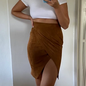 Mockakjol med slits  - En högmidjad mockakjol i materiel av polyester. Bra skick knappt använd och är otroligt bekäm med snygg passform. Kjolen är Stl S men har ett stretchigt matriel så passar på mig som vanligtvis har M/L och min längd är 175cm. Frakt tillkommer. 