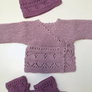 Bebiskofta med sockor och mössa - Stickat set till bebis i storlek 6/9 månader bestående av ljuslila omlottkofta samt mörkare sockor och mössa. Köparen står för frakt samt köpt är köpt. Hör av dig för mer närbilder eller frågor!