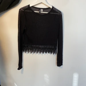 H&M topp - En svart långarmad söt tröja men nötliknande material och spets längst ner.  Kunden står för frakt, inga byten.
