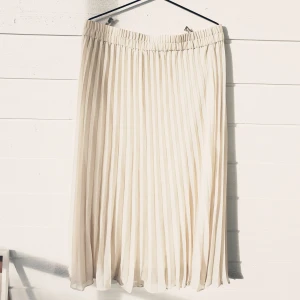 Plisserad Midi/Maxikjol från Monki Strl. L (Ny!) - Säljer en cremevit kjol från Monki som aldrig har använts så den är så gott som ny! Kjolen har ett underkjol som går ner till kjolens kant.