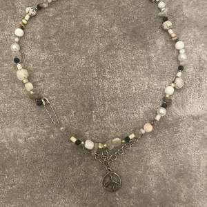 Egentillverkat halsband med olika pärlor och peace charm.