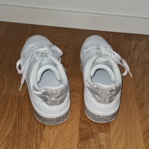 Vita glittriga snaekers - Vita sneakers med glittrig plattå. Storlek 39. Använda några gånger, men rengjorda noggrannt och inga fula märken på dom! Bra passform. 