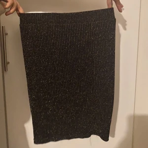 Kort kjol - En svqrt kort kjol me gulidgt glitter. utmärkt till att gå ut i då glittret är väldigt passande festlikt. Kjolen är helt oanvänd och i nyskick