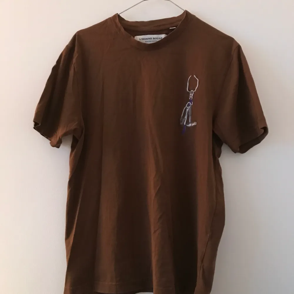 Säljer en t-shirt från det nedlagda märket L’Homme rouge i färgen brun. Size 48/M, sitter lite mindre.. T-shirts.