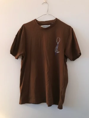 L’Homme rouge t-shirt - Säljer en t-shirt från det nedlagda märket L’Homme rouge i färgen brun. Size 48/M, sitter lite mindre.