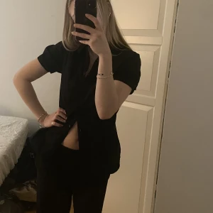 Svart topp - Jättesöt svart topp i skjortmaterial, köpt begagnat och sitter fint men får tyvärr inte användning för så mycket och behöver pengar! 100kr