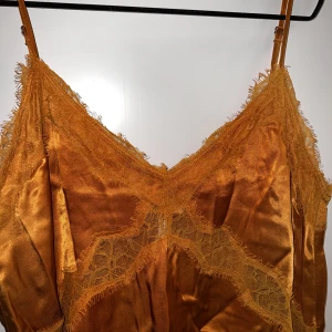 Linne med spets  - Säljer ett linne i brons färg med spets. Aldrig använd, etikett kvar.