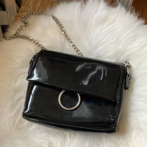 Axelväska - En liten axelväska i blank svart. Skriv om du är intresserad av mått eller allmänt mer info. Har lite små slitage, men inget jättesynligt. Från Don Donna. ✨